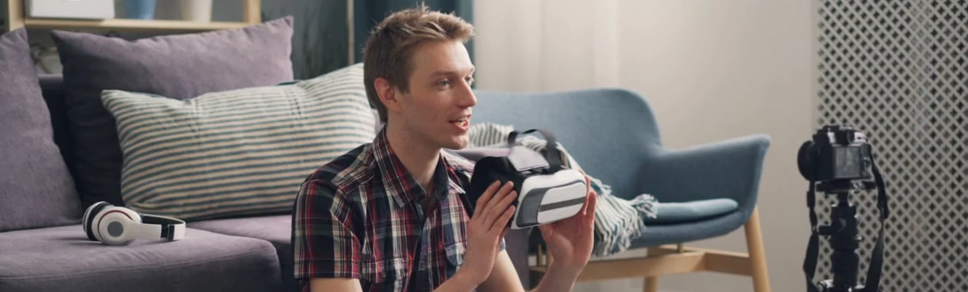 Creator filming content in a living room studio, holding a VR headset next to a camera on a tripod
